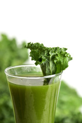 kale smoothie in a glass topped with a kale leaf