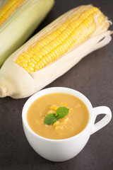 Corn soup in bowl and sweet corn on plate


