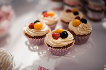 Tasty cupcakes with cream decorated with berries