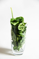 Spinach leaves in a glass on a white background.