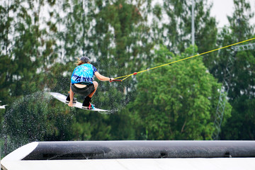 Wake boarding rider jumping and flying trick with water splash in wake park, active extreme sport for healthy ,recreation and hobby.