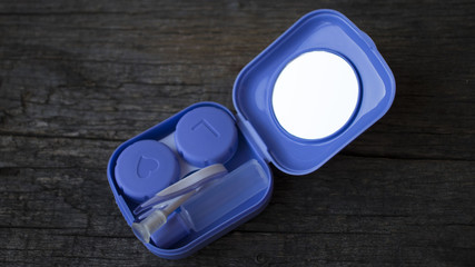 Contact lenses, tweezers on in pack on wooden background. contact storage container