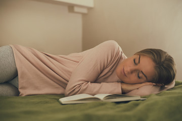 Beautiful woman fall asleep while reading a book.