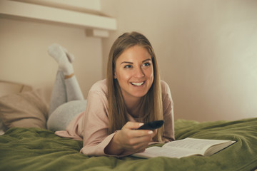 Beautiful woman enjoys reading a book and watching tv.