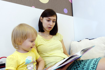A young mother reads a children's book for a child.