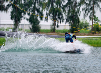 Wake boarding rider jumping trick with water splash in wake park, active extreme sport for healthy ,recreation, hobby or adventure