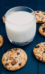 Chocolate chip cookies and glass of milk on dark background