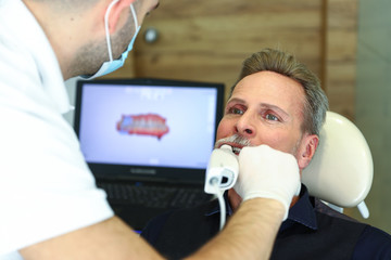 Dentist reviewing man with 3d tooth scanner
