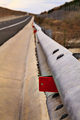 Steel guard rail barrier on the highway red reflective sign