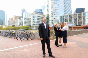 Male boss looking at watch near employees talking in background. Concept of work planning and time...