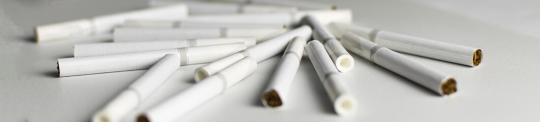 Many cigarettes lie on a light background.