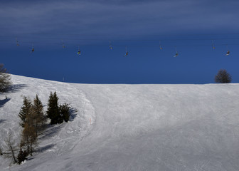 Winding snowboard trace and chairlift shadow on white snow