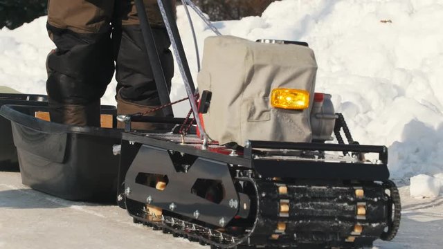 Crawler mini snowmobile with a trailer going on a winter road