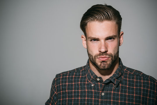 Portrait of serious and confident handsome bearded man in checkered shirt. Isolated on grey background. Copy space area for advertising, text or slogan.