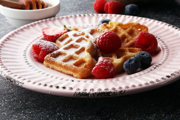 Traditional belgian waffles with fresh fruit and powder sugar on wooden board