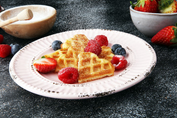 Traditional belgian waffles with fresh fruit and powder sugar on wooden board