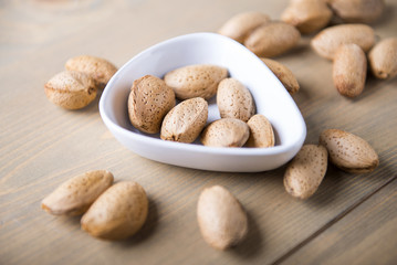 Almonds in white shell on wooden table