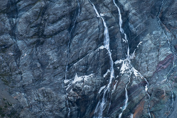 Black tall cliff with ice and waterfall begining of the glacier in Mt Cook National Park.
