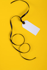 White tag with black ribbon on background