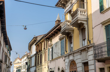 Fototapeta na wymiar mediterranean facades / Street with pretty, beautiful, houses in Verona with balconies and blue sky 
