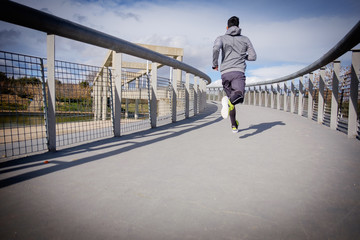 Young athlete man running in a city park