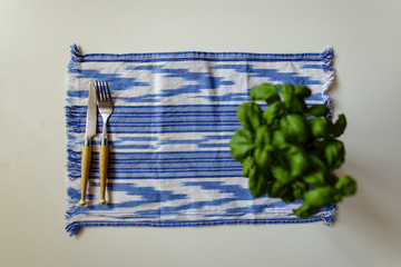 Basil against a blue tablecloth and cutlery