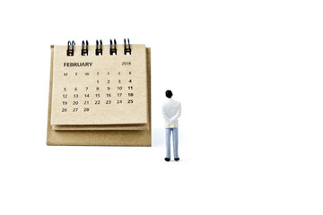 February. Calendar sheet and miniature plastic man on white background.