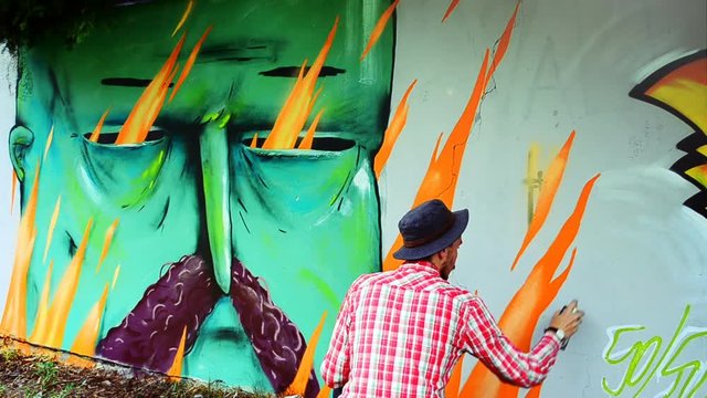 The artist draws graffiti on a fence.	Abstract drawing.