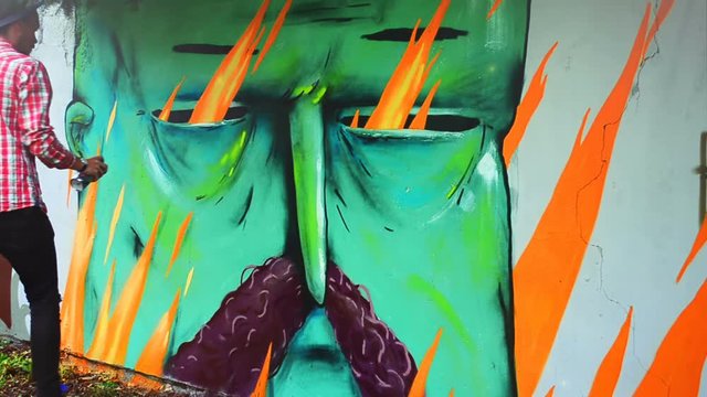 The artist draws graffiti on a fence.	Abstract drawing.