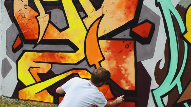 The artist draws graffiti on a fence.	Abstract drawing.