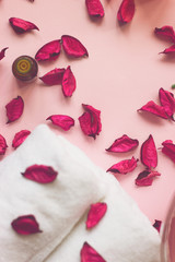 Pink potpourri, white towels, scented sticks and aromatic oil on pink background; spa or wellness background