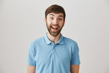 Fototapeta premium So happy to see you. Studio shot of enthusiastic funny male employee smiling cheerfully and lifting eyebrows in surprise, standing over gray background. Mature man unexpectedly met his school mate