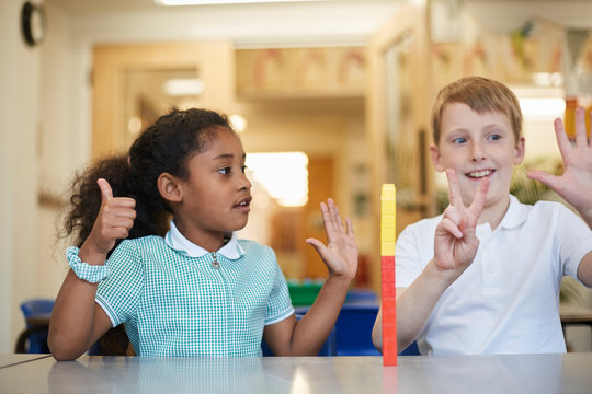 Schoolboy and girl counting on fingers in classroom at primary school