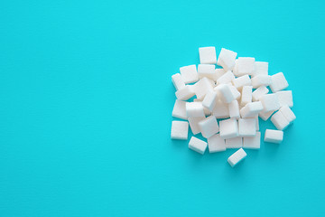 Sugar cubes scattered on a blue background with an empty space for text copy paste
