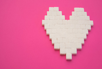 Heart made of cubes of sugar. Sugar kills. Pink background. Empty space for copying text.