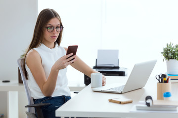 Business young woman using her mobile phone in the office.
