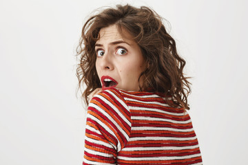 Do not sneak up, you scared me. Studio shot of scared woman turning back to camera, expressing...