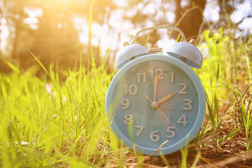 Image of spring Time Change. Summer back concept. Vintage alarm Clock outdoors.