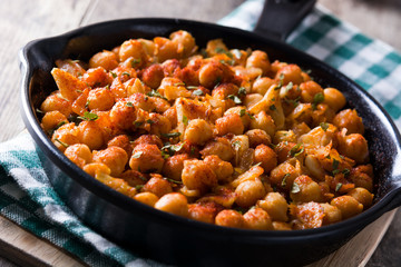 Close up fried spicy chickpeas in frying pan on wooden table