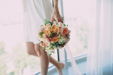 bride with a beautiful bouquet of different flowers in the hotel