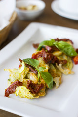 Raw food salad of fresh vegetables and sun-dried tomatoes in a white plate on the table