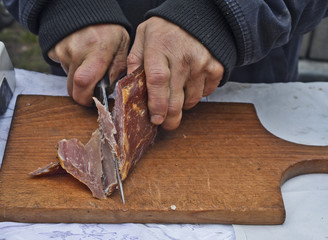 Man is cutting dry meat for tasting