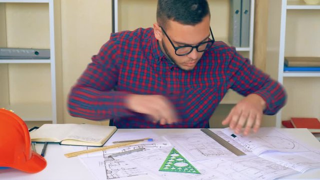 young builder works in the office mixed race student architect working with building plan. holding a ruler measures objects