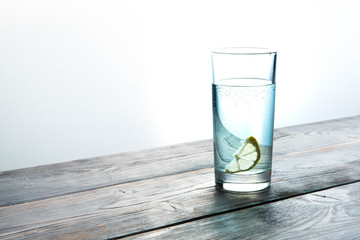 glass of crystal-clear water on a wooden background with a lemon slice