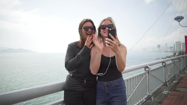 Lesbian couple talking by video on phone on bridge at sunrise rapid slow motion