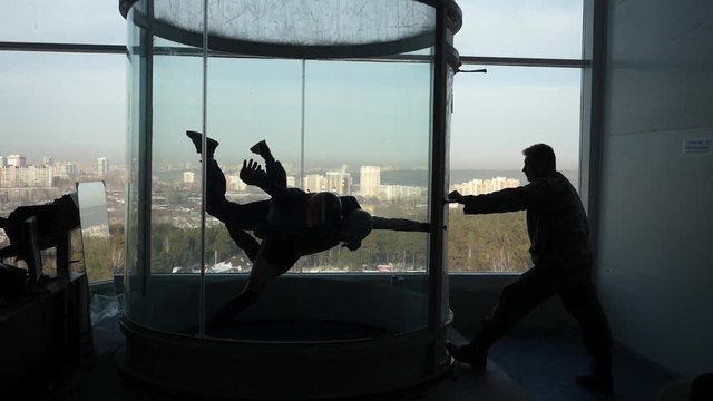 Male instructor helps man to fly inside air-tube. Training flight in an air tube with an instructor