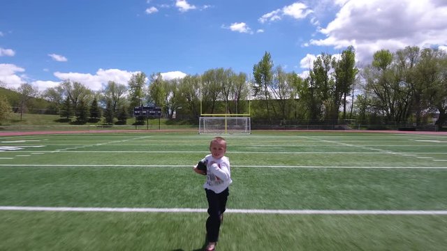 Seriouse young boy running with a football