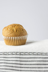Homemade Whole Wheat Bran Muffin on White Cotton Kitchen Towel. Breakfast Morning Healthy Pastry Baking Concept. Minimalist Style Copy Space for Text