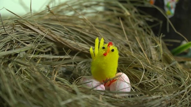A toy chicken sits on quail eggs in a nest