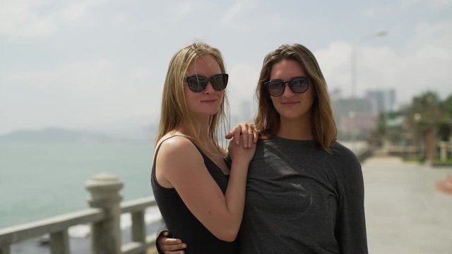 Happy lesbian couple in sunglasses look at the camera sunset rapid slow motion